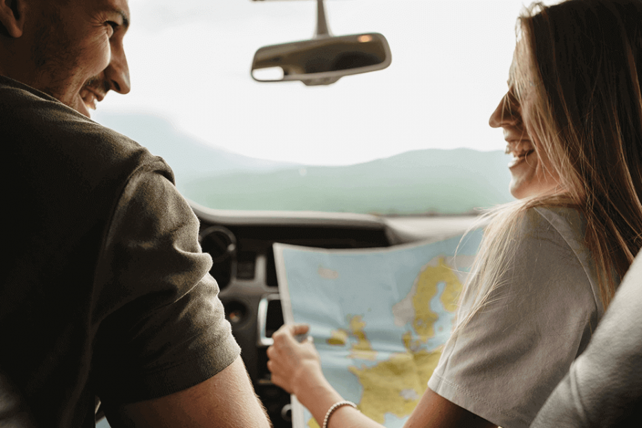 pareja planificando un viaje en coche de alquiler con un mapa